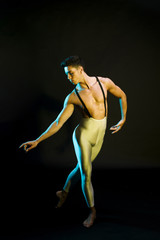 Graceful male ballet dancer performing in spotlight