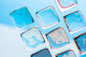 Stylish blue background with transparent ice-like cubes for drinks. Flat lay macro photo.