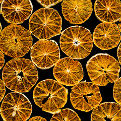 Ornament of homemade orange chips on a black background. The concept of organic food and healthy snack.