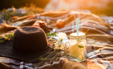 Summer picnic outdoors, summer drink jar with lemonade, plaid in the warm sunlight