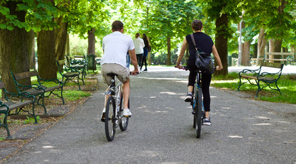 Zwei junge Menschen fahren mit dem Fahrrad durch einen schönen Park