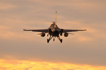 Reactor de combate F-16 aterrizando al anochecer