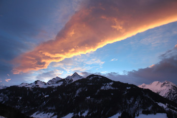 Magical colorful sunrise with a unique cloud constellation over snow-covered peaks in the alps.