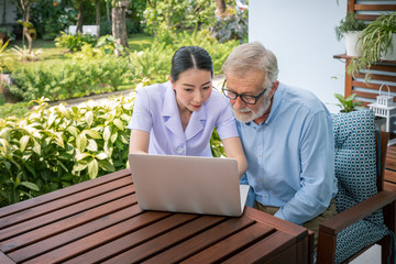Caregiver assist senoir eldery man using notebook laptop computer connect to Internet