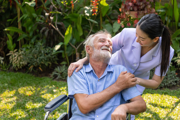 Happy nurse take care elderly man on wheelchair in garden at nursing home