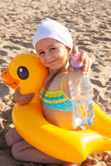 The child drinks water on the beach
