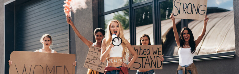 panoramic shot of five screaming multiethnic feminists holding smoke bomb, loudspeaker and placards with feminist slogans - obrazy, fototapety, plakaty
