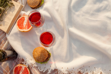 Romantic picnic at sunset. Picnic basket with red wine, bread and fruit