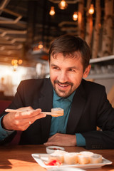 A man in costume eats sushi in a restaurant