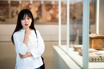 Chinese woman standing in art museum near the painting in baguette