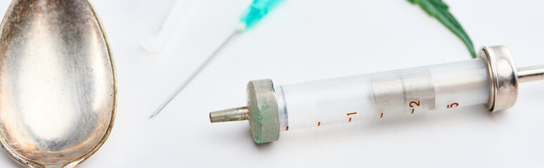 close up view of spoon, syringe and needle on white background, panoramic shot