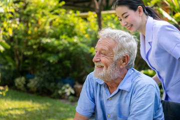 Happy nurse take care elderly man on wheelchair in garden at nursing home