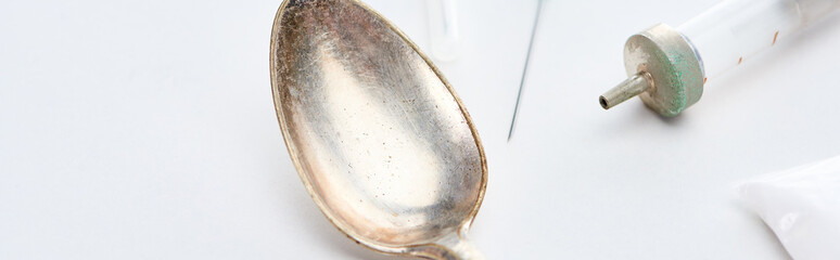 close up view of silver spoon, heroin, syringe and needle on white background, panoramic shot