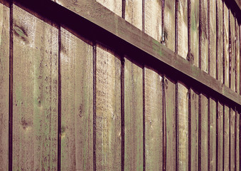 A wooden fence with vertical panels and horizontal cross bar in closeup