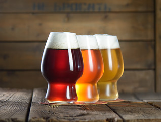 Different beer in glasses on wooden background