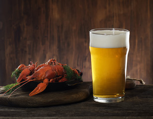 glass of beer and boiled crayfish wooden background