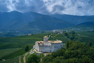 Fototapeta na wymiar Panoramic view of the Castel Belasi region of Trento north of Italy. The castle is surrounded by nature, vineyards, fruit tree plantations in a quiet location. Aerial view.