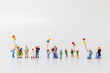 Miniature people holding balloon isolated on white background and copy space for text