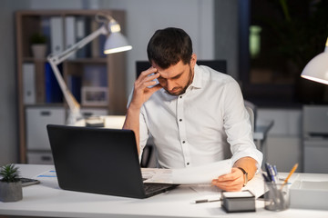 Obraz premium business, deadline and people concept - businessman with papers working at night office