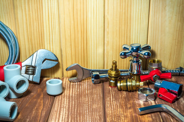 Plumbing repair supplies and tools on wooden, antique background.