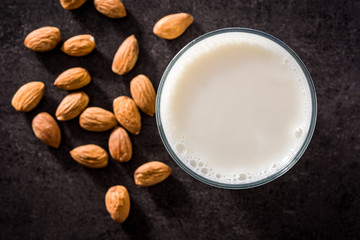 Almond milk in glass on black background. Top view