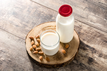 Almond milk in glass and bottle on wooden table