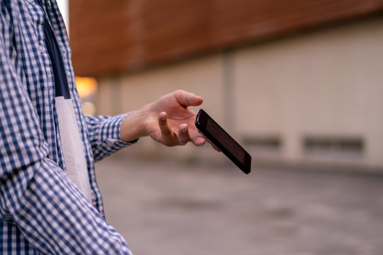 person holding a smartphone in the street, a phone falling and flying  down by an accident