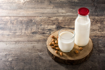 Almond milk in glass and bottle on wooden table. Copyspace