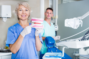 Dentist explaining correct tooth brushing on dental model