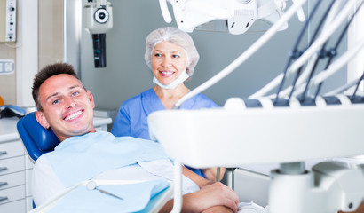 smiling man sitting in dental chair waiting for medical examination