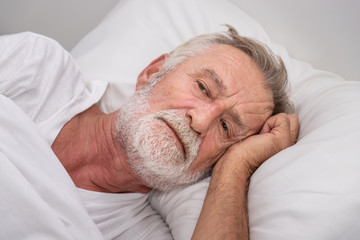 Senior elderly man on bed eye open sleeplessness and worry, with white blanket in bedroom