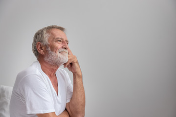 Senior elderly man sitting on bed and try to remember after waking up in morning