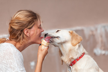  young woman with her dog eating ice cream from a waffle cone outdoor