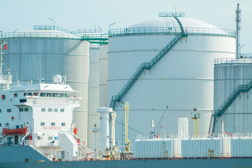 Oil tanker with a background of oil warehouse storage tanks in Rotterdam
