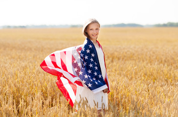 patriotism, independence day and country concept - happy smiling young girl wrapped into national american flag on cereal field