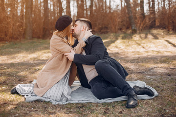 Couple in a park. Blonde in a brown coat. Man with a beard