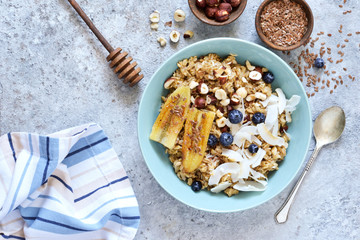 Oatmeal with caramel, banana, blueberries and coconut chips on a concrete background.