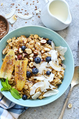 Oatmeal with caramel, banana, blueberries and coconut chips on a concrete background.