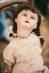 Scary porcelain doll on a chair at a flea market