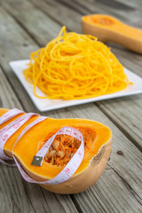 Measuring tape wrapped around butternut squash cut in half with low carb noodles