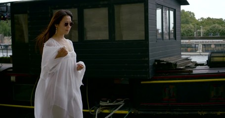 pretty woman is wearing white dress is walking alone in harbour in city in daytime