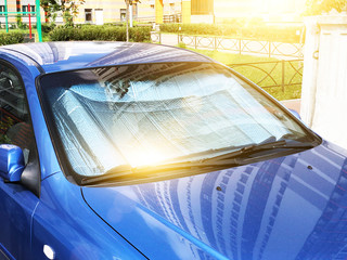 Protective reflective surface under the windshield of the passenger car parked on a hot day, heated...