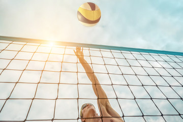 Beach Volleyball player in sunglasses in action with ball under
