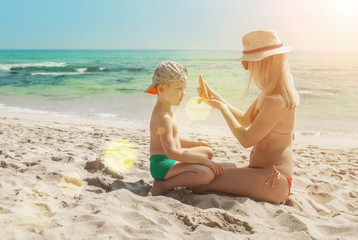 Mother applying sunscreen protection creme on cute little toddle