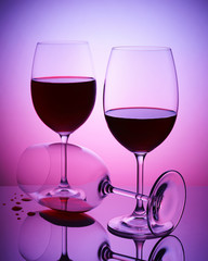 Transparent wine glass with red wine on violet background