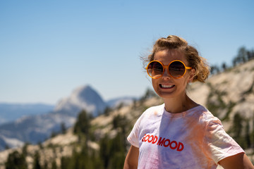 Adorable brunette young woman poses at Olmstead Point in Yosemite National Park. Half dome blurred...