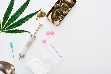 top view of marijuana buds, cannabis leaf, spoon, heroin, lsd and syringe on white background