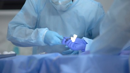 Surgeon using scalpel to cut patient body on operation table, medical healthcare