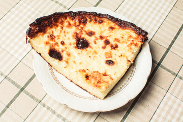 Piece of tender casserole of cottage cheese and eggs on saucer.