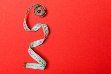 Tangled measuring tape with space for your idea. Sewing and tailor concept on red background